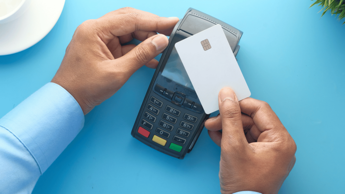 Credit card being swiped or tapped on a modern payment terminal to complete a transaction. The image highlights seamless digital payments, emphasizing financial responsibility and the importance of making smart purchases to save money.