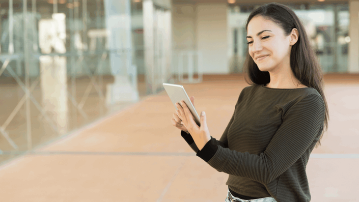 A satisfied customer smiles as she uses a tablet, illustrating the personalized and positive user experiences created by AI for SMEs.