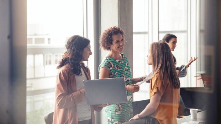 A group of female entrepreneurs networking in a modern office, discussing business strategies and growth opportunities.
