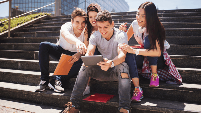 Diverse group of happy young professionals collaborating around a laptop displaying social media analytics, strategizing an influencer marketing campaign.