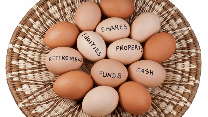 A woven basket contains several eggs, some of which have words written on them such as "SHARES", "EQUITIES", "PROPERTY", "RETIREMENT", "FUNDS", and "CASH", representing different types of investments and the importance of diversification to avoid investing mistakes.