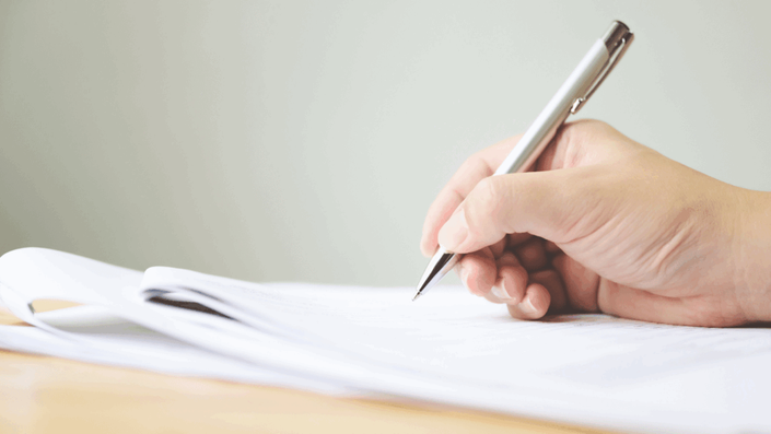 A close-up of a person's hands carefully filling out an official application form titled "Wohngeld," illustrating the process of applying for this German housing benefit.