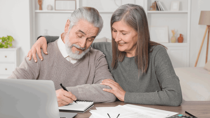 Senior couple discussing pension planning and reviewing financial documents at home, focusing on financial literacy for retirement planning.