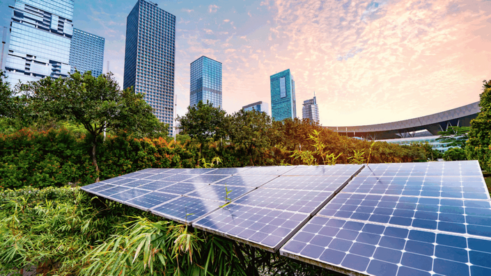 Solar panels are installed in a lush green urban park with modern skyscrapers in the background, symbolizing sustainable technologies and green business models, which are excellent business ideas for young founders.